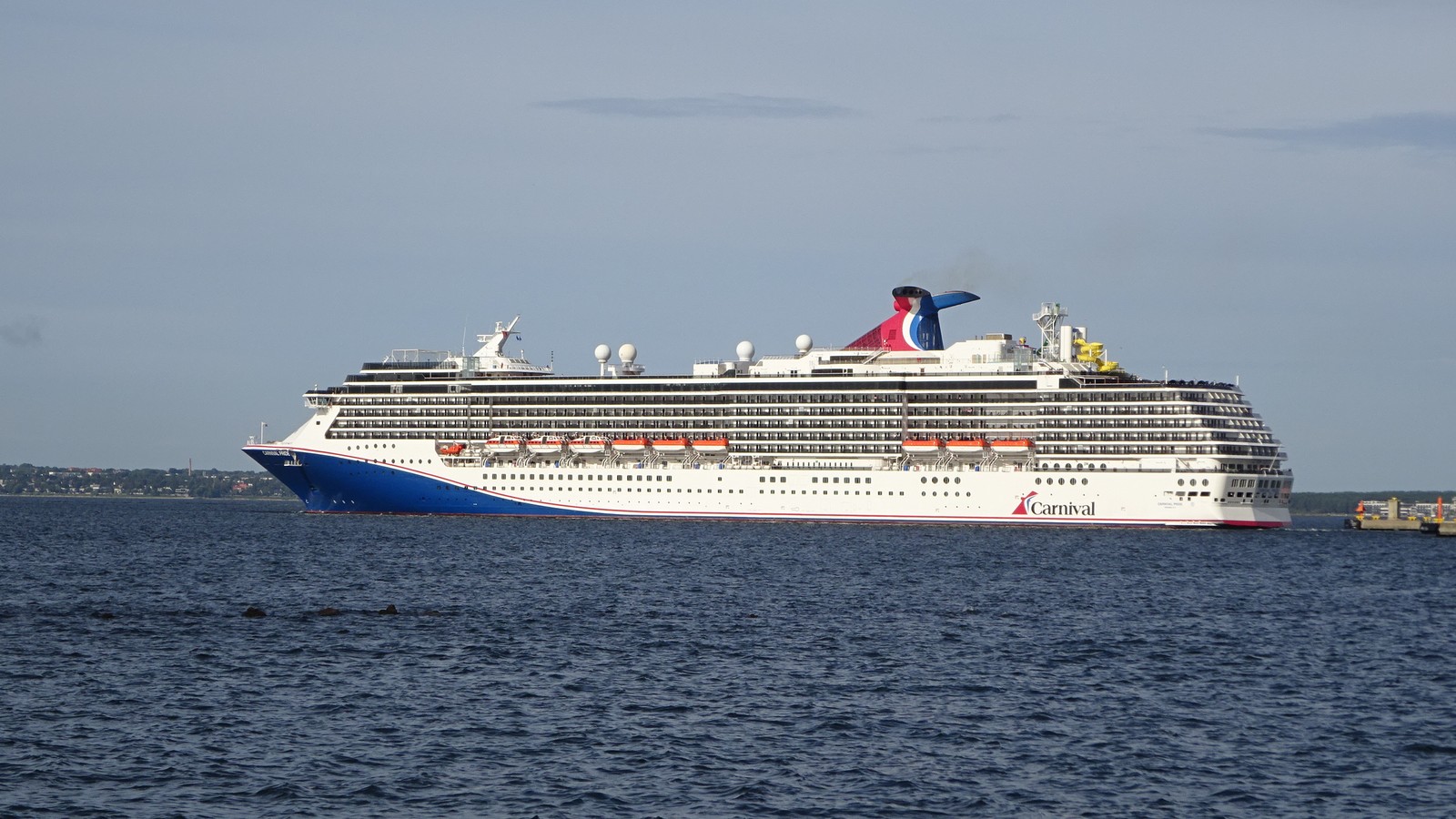 Carnival Pride cruise ship departing port under clear skies