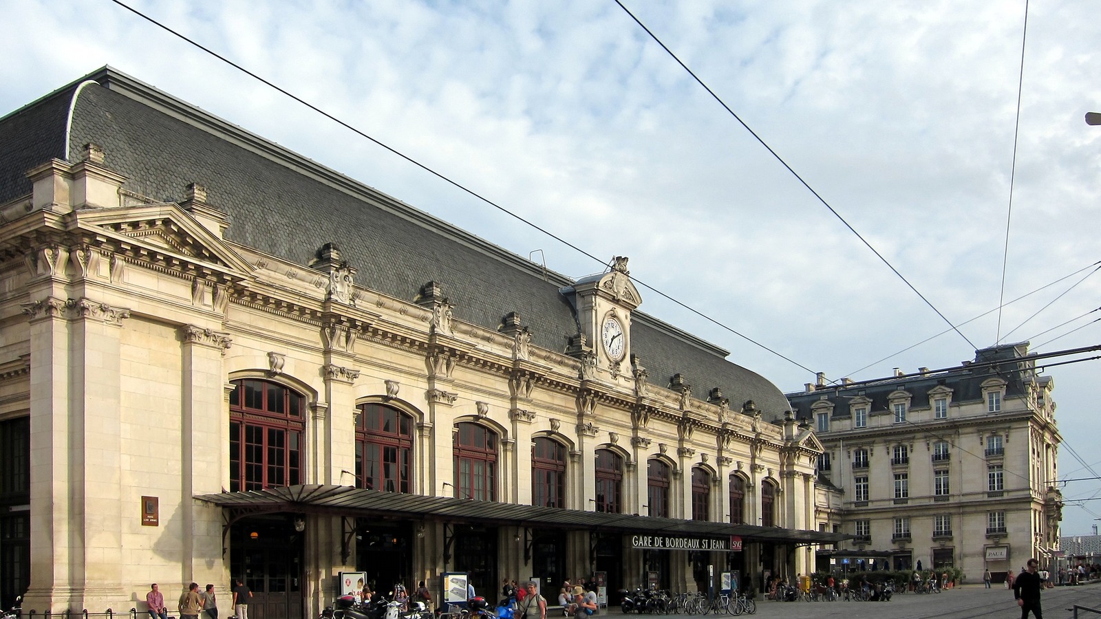 Exterior of Gare de Bordeaux Saint-Jean station with SNCF signage and travelers in the forecourt