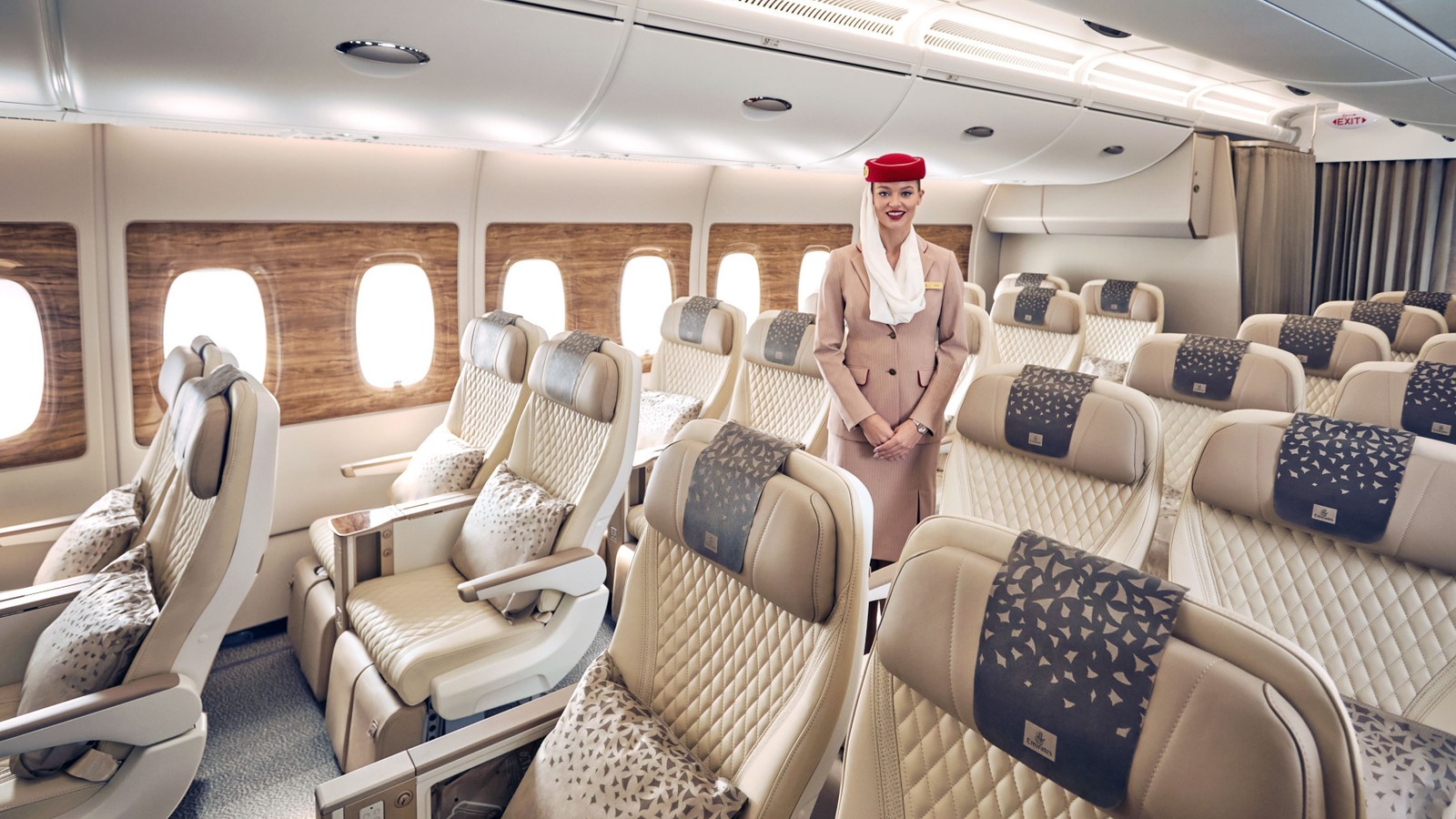 Emirates Premium Economy cabin with cream seats and a cabin crew member