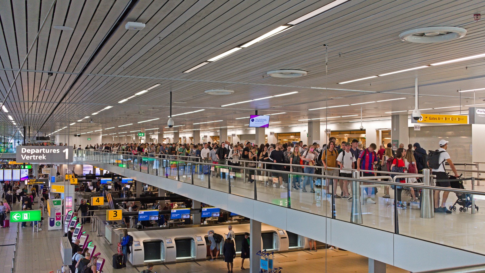 Passengers queue near the security control area in the departures hall at Amsterdam Airport Schiphol