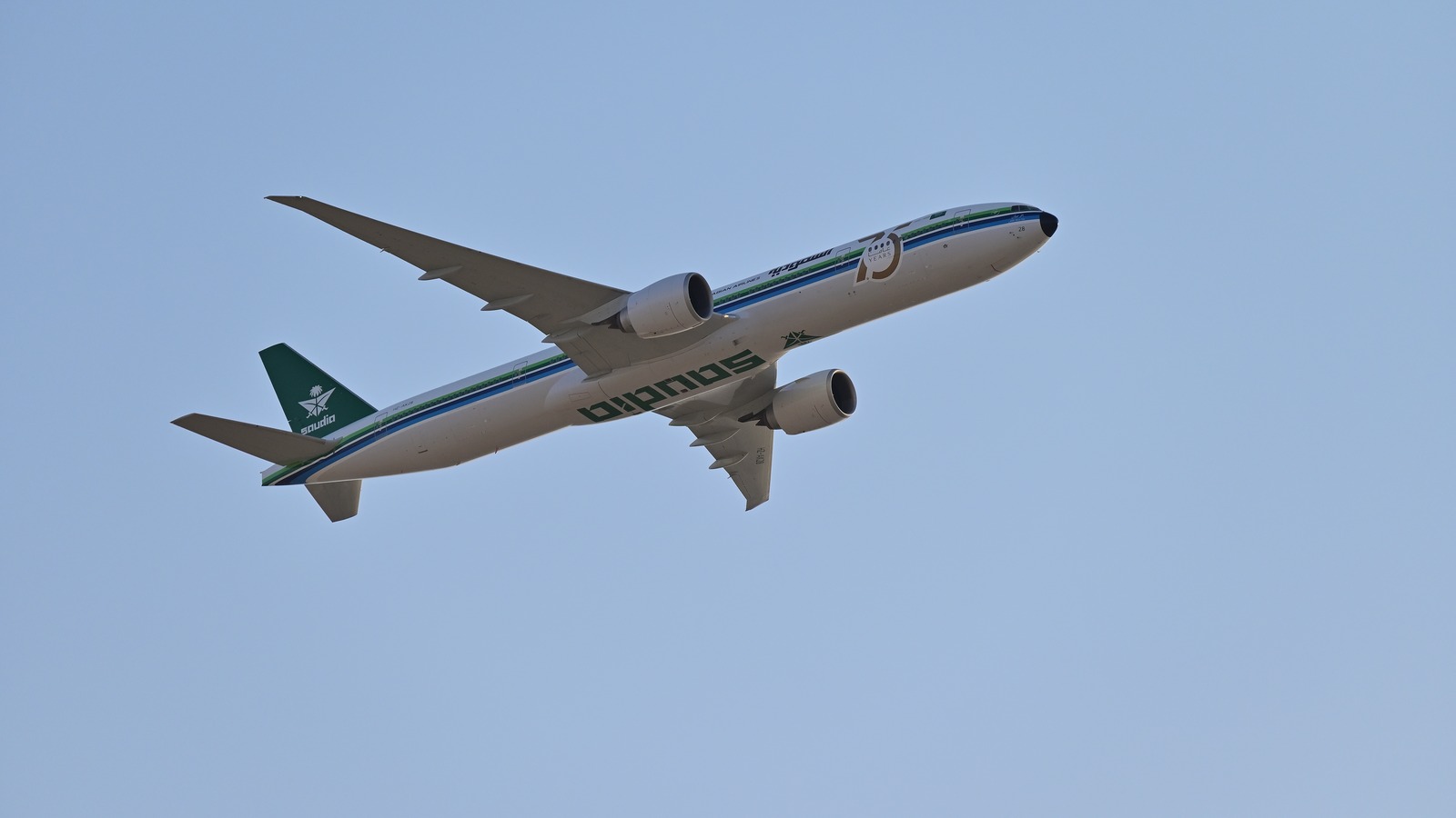 Saudia Boeing 777-300ER in flight against a blue sky