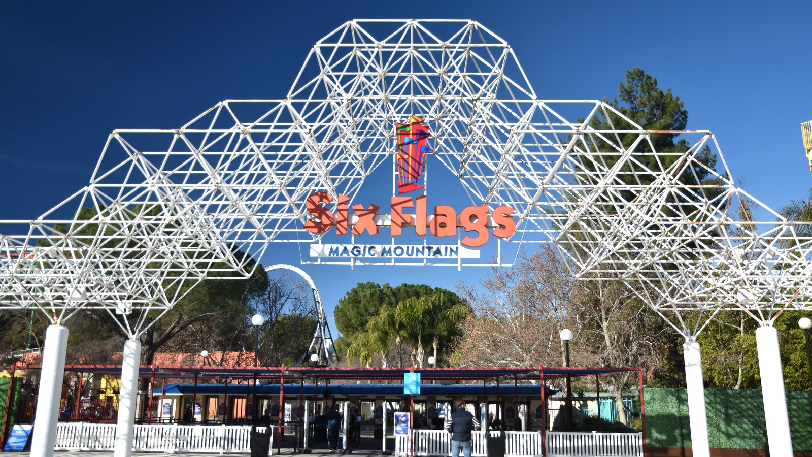 Daylight Six Flags Magic Mountain entrance arch in Valencia with a readable park name on the metal lattice