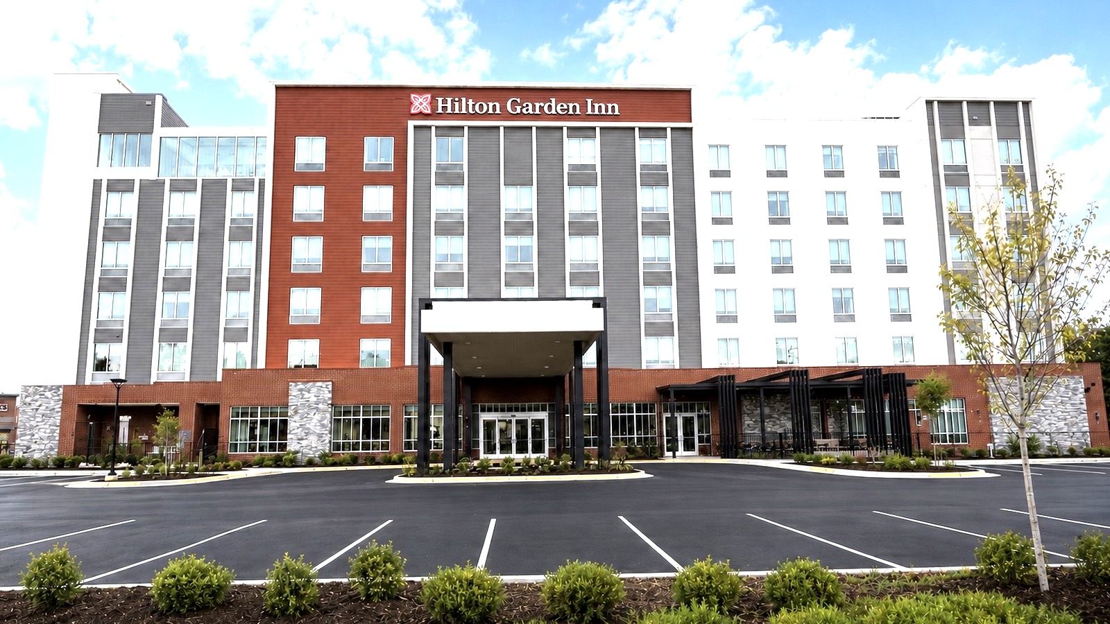 Exterior of Hilton Garden Inn Steele Creek Charlotte with outdoor seating and pool terrace