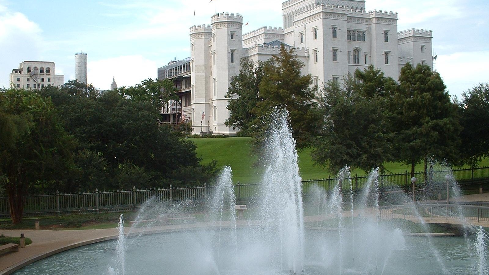 The white castellated Gothic Revival Old State Capitol in Baton Rouge seen behind a working fountain and green lawn