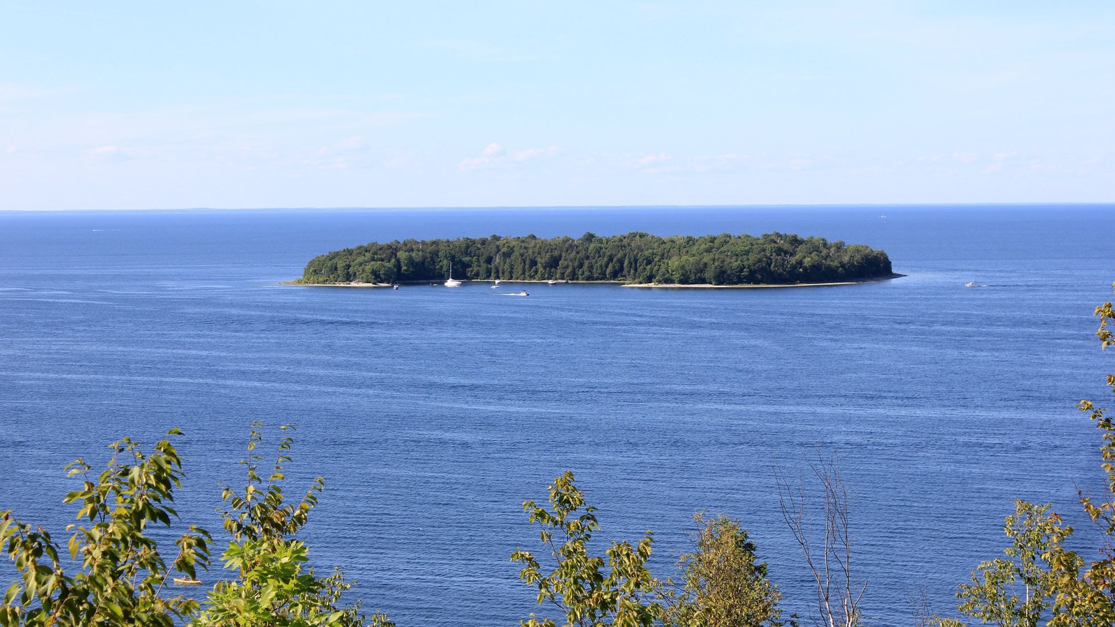 The wooded low outline of Horseshoe Island in the blue water off Peninsula State Park in Door County, Wisconsin