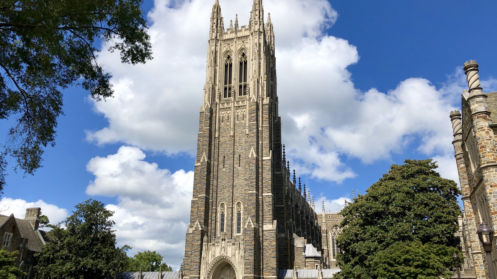 The Gothic stone tower of Duke Chapel on Duke University West Campus rising against a blue sky with clouds