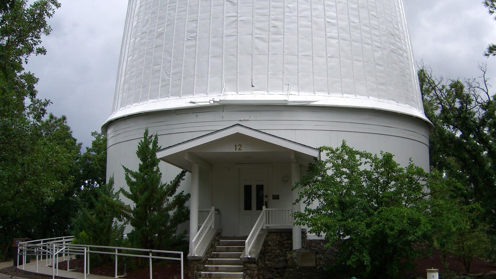 The white domed housing of the Clark Telescope at Lowell Observatory in Flagstaff, Arizona, among pines under a bright sky