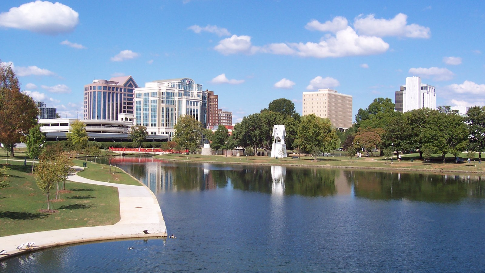 The downtown Huntsville skyline reflected in the lagoon at Big Spring International Park under a blue sky