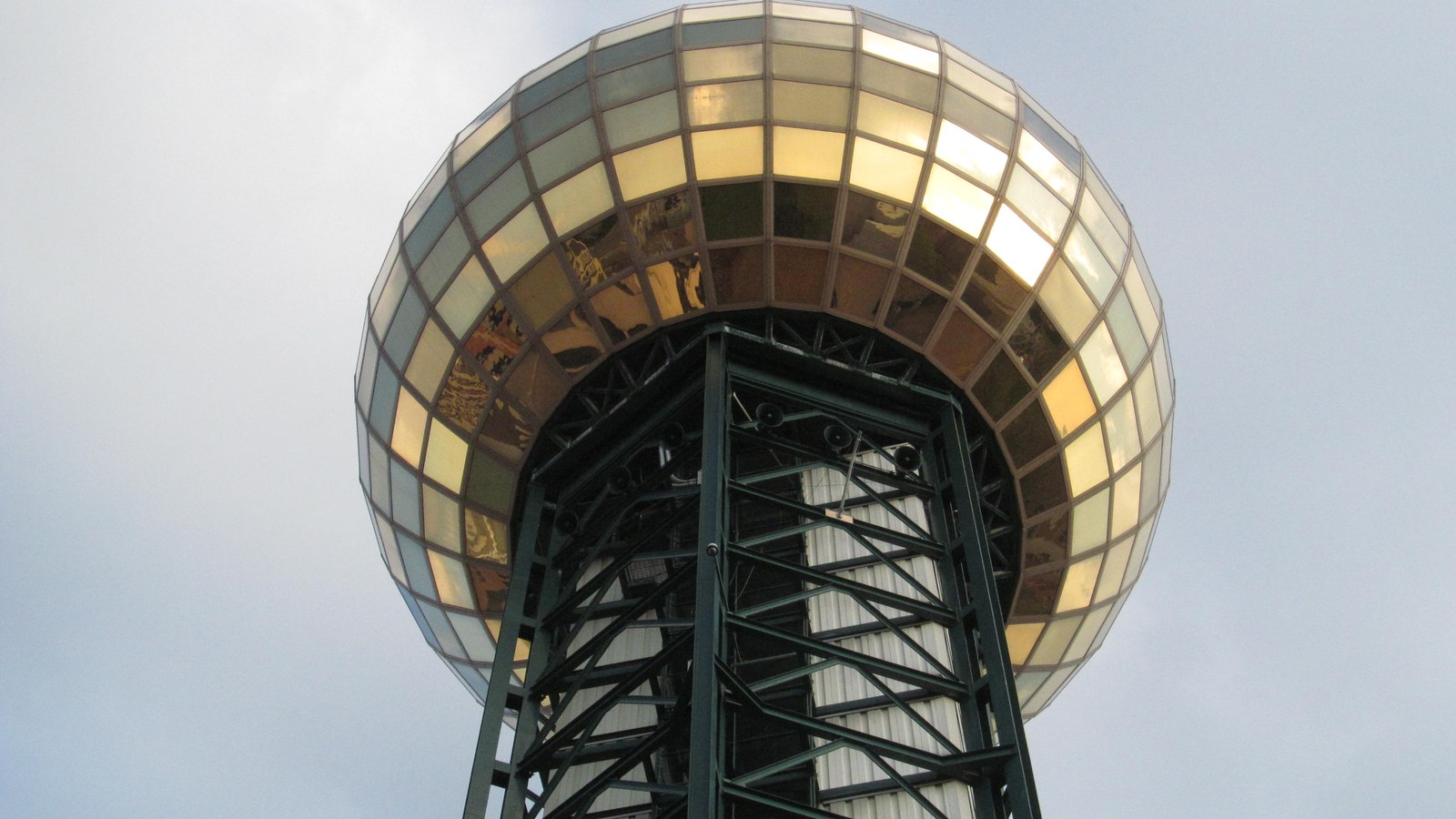 The gold glass Sunsphere tower of the 1982 World's Fair rising on its steel legs above Knoxville against a pale sky