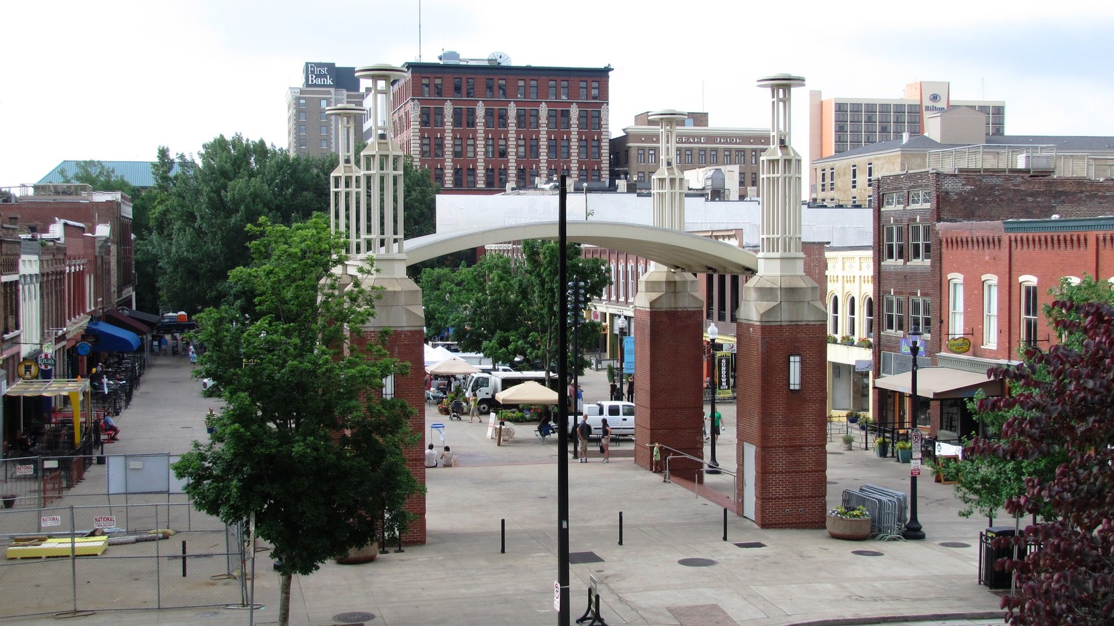 The brick pillars and arch at the north end of Market Square in Knoxville, with market canopies and downtown buildings behind