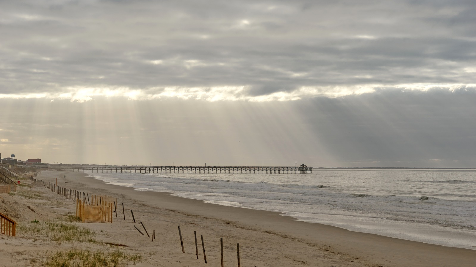 Oak Island beach and pier beneath morning sun rays