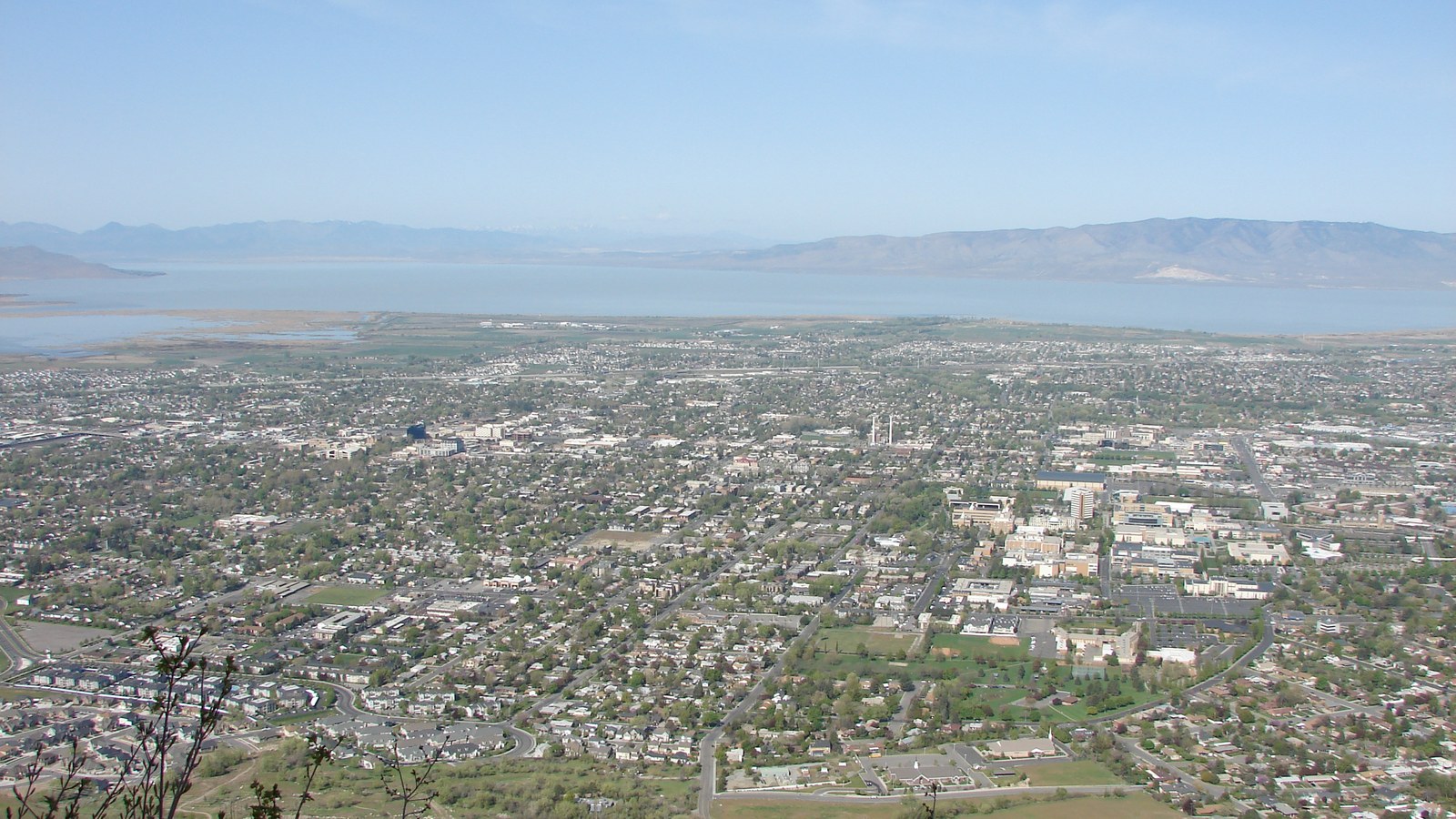 A high view over the grid of north Provo, Utah, from the Y trail on Y Mountain, with the broad pale expanse of Utah Lake and the far shore mountains beyond