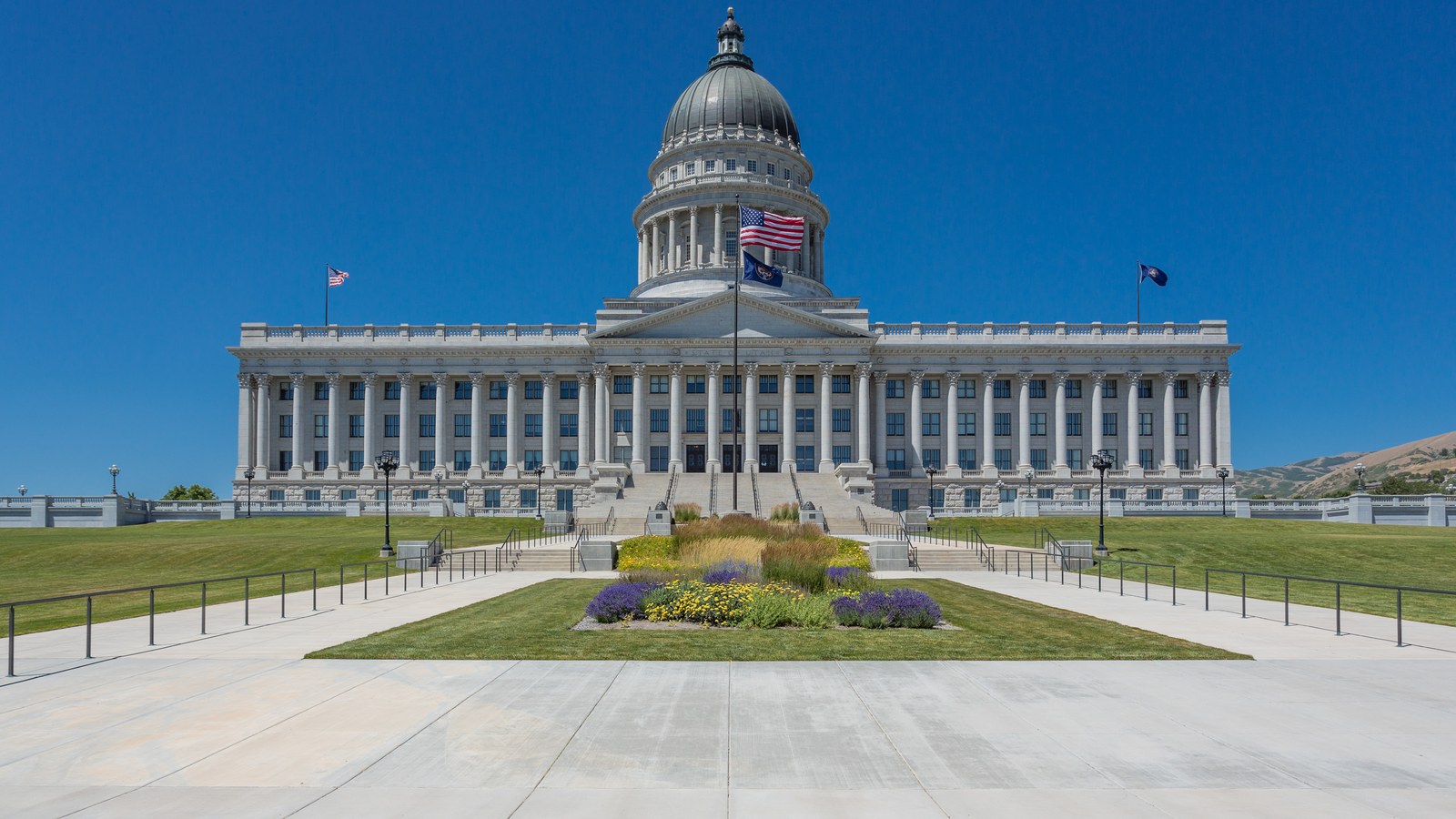 The domed front of the Utah State Capitol in Salt Lake City above a flower bed under a clear blue sky