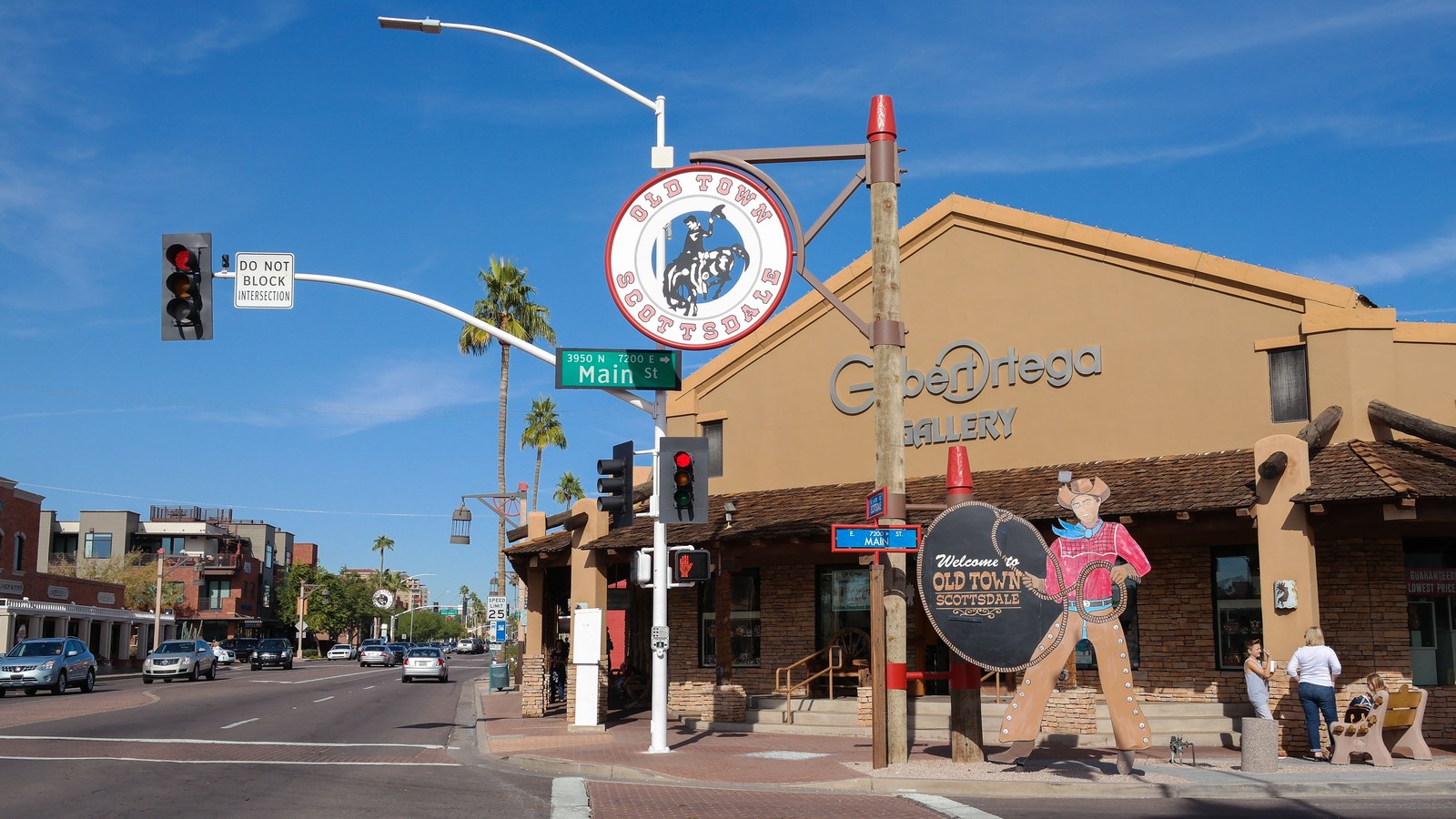 Storefronts and palm trees along a sunlit street corner in Old Town Scottsdale, Arizona under a clear blue sky