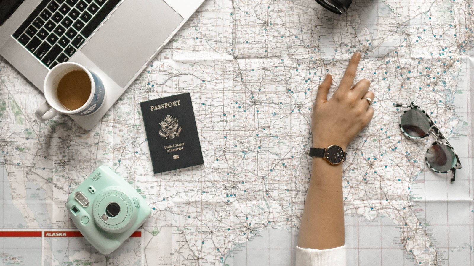 A traveler planning a route with a map, laptop and camera