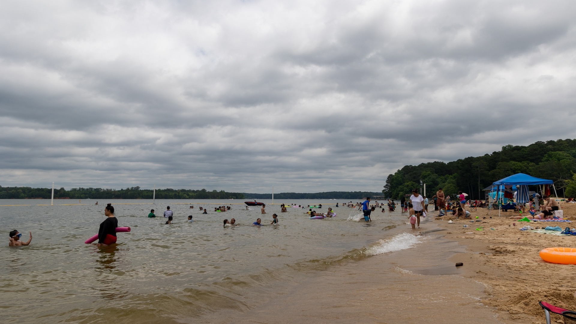 People swimming and standing in the shallows at the Galt's Ferry swim beach on Lake Allatoona in Georgia
