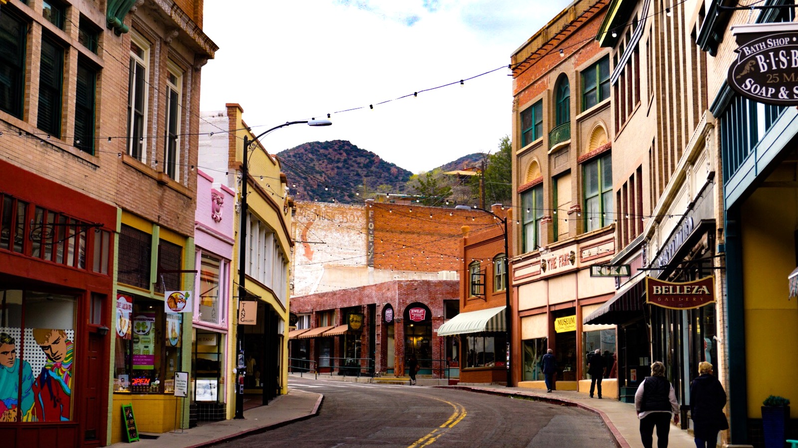 Main Street in Old Bisbee, Arizona, a narrow canyon street lined with brightly painted historic storefronts and awnings