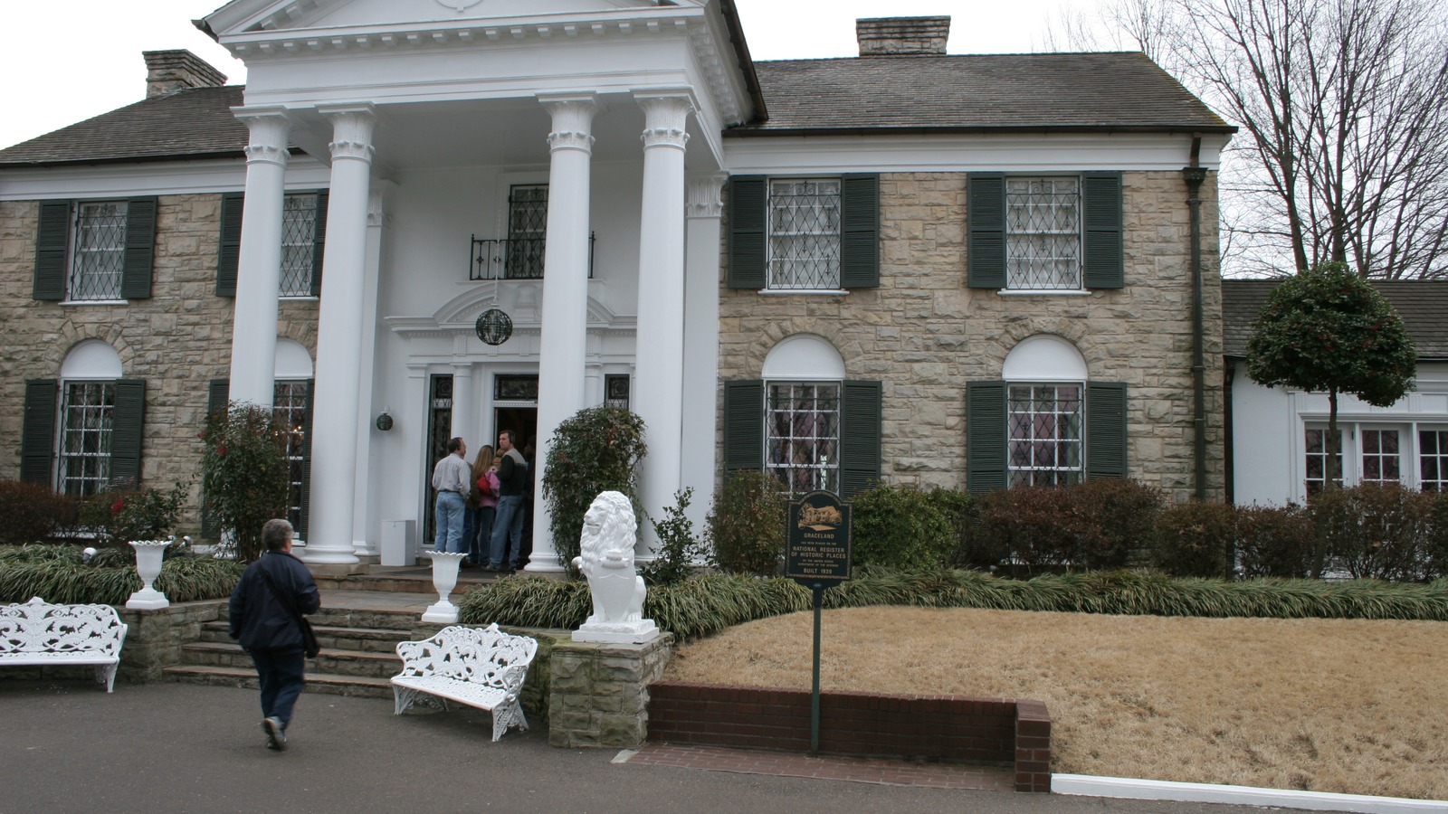 The white columned front facade of the Graceland mansion in Memphis with its stone lions and lawn