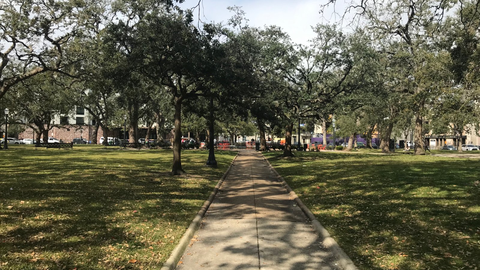 A tree lined pedestrian pathway under mature live oaks in Bienville Square, downtown Mobile, Alabama