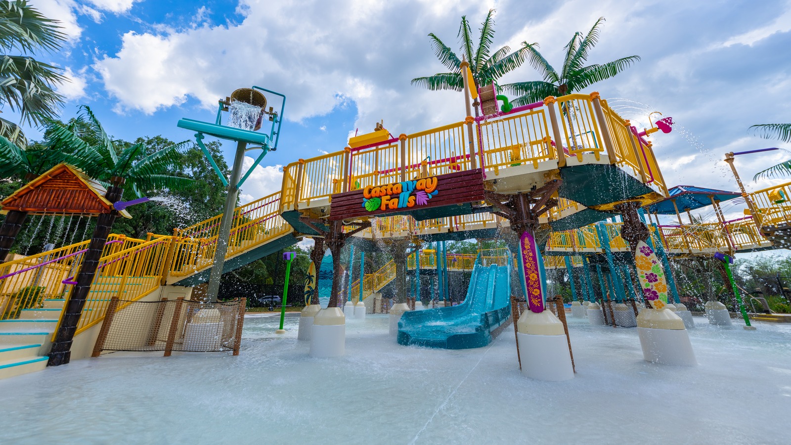 Castaway Falls sign, raised yellow-railed play structure, tipping bucket and small blue slide at Adventure Island