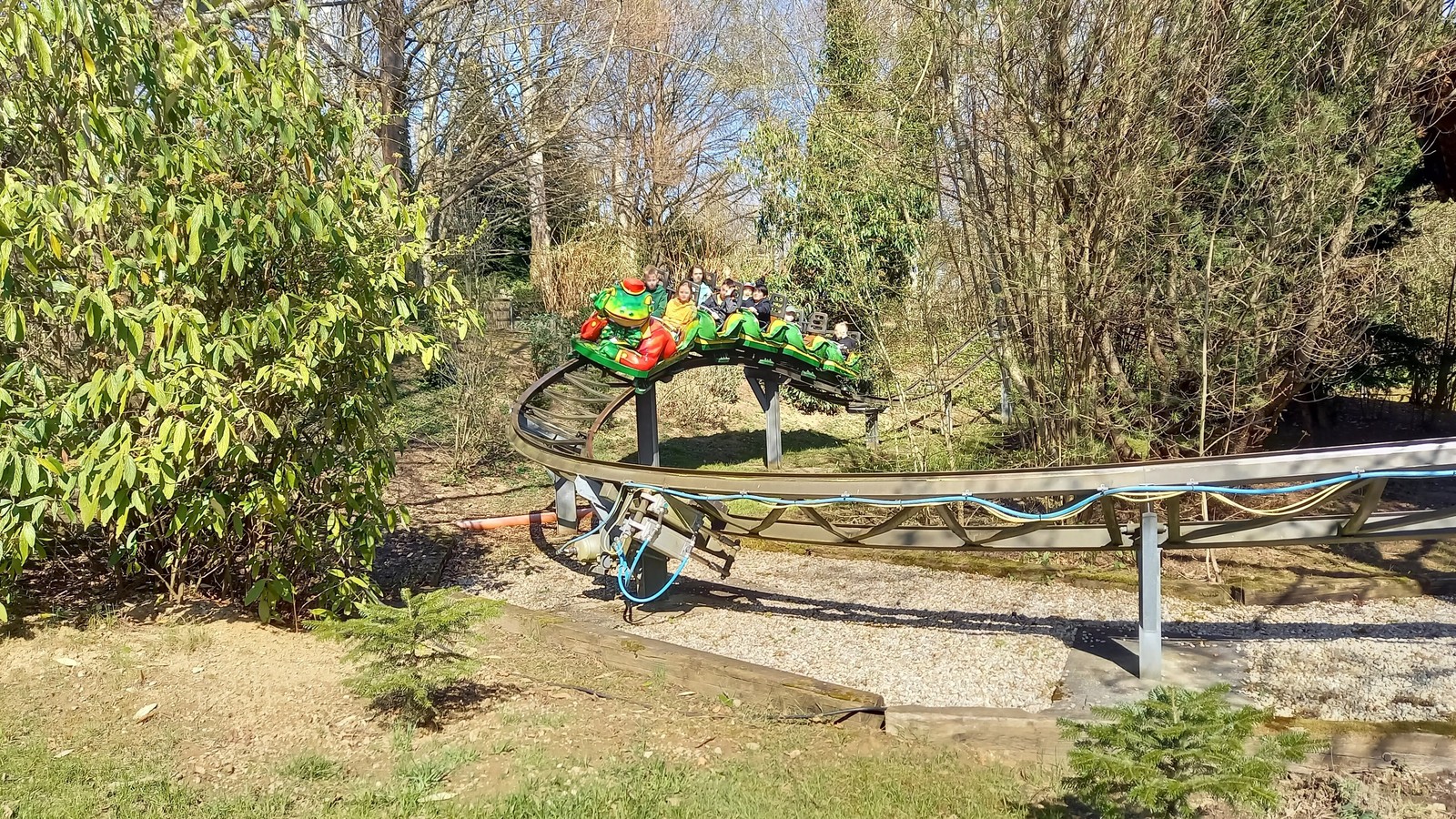 Green frog themed Froschbahn coaster train on its track at Bayern-Park