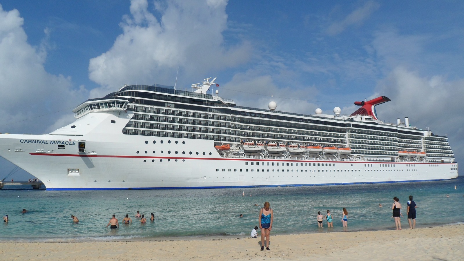 Carnival Miracle offshore in daylight with the ship name visible on the bow