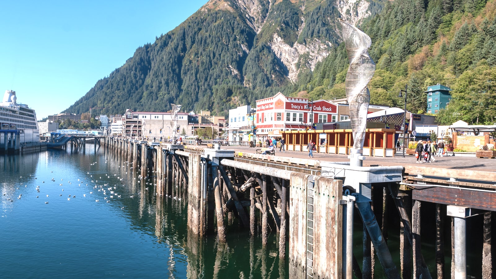 Oceania Regatta cruise ship docked along the Juneau, Alaska waterfront with downtown and mountains behind the harbor