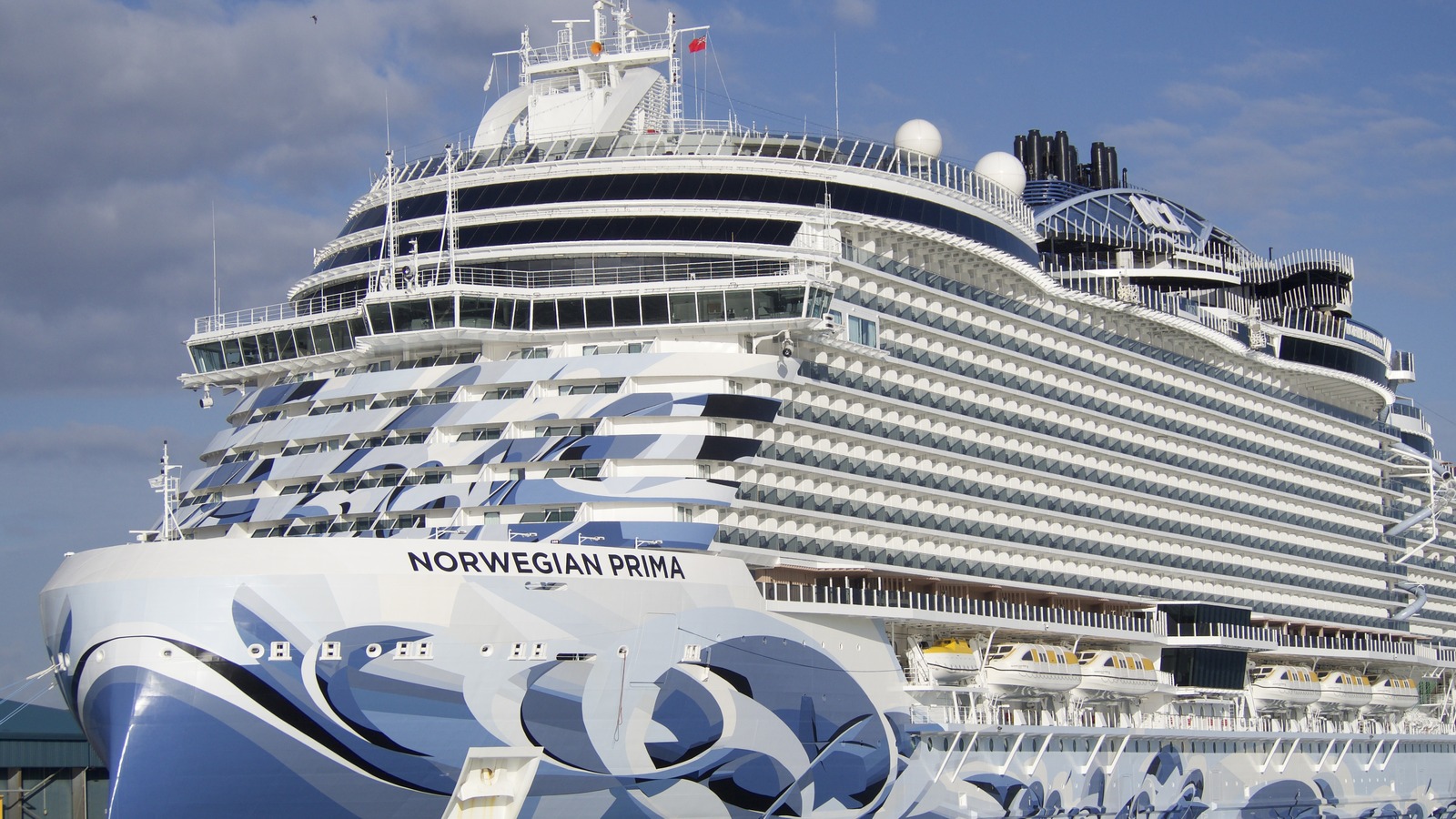 Norwegian Prima cruise ship at berth showing its name on the bow and blue wave hull art