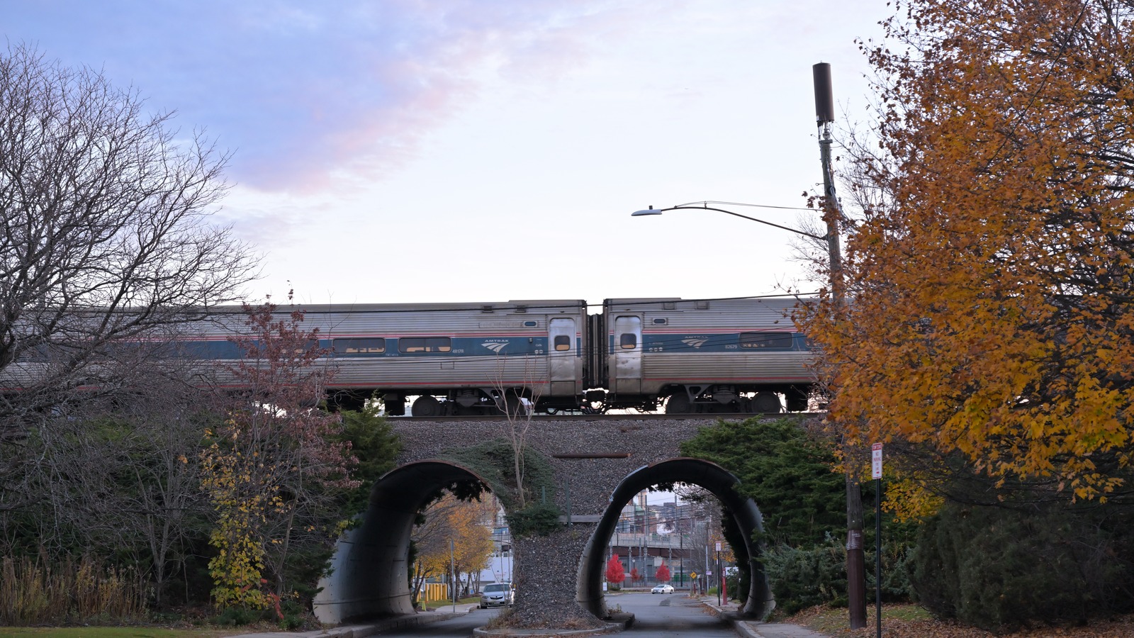 Amtrak Downeaster passenger cars crossing a road overpass in autumn