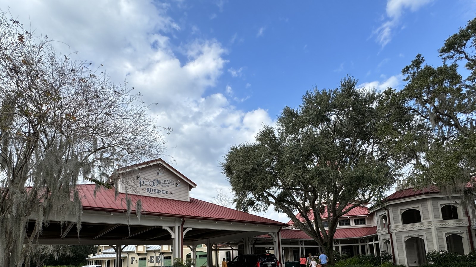 The porte cochere entrance to Disney's Port Orleans Resort Riverside in January 2024, the resort sign above a red roof with Spanish moss hanging from the oaks on either side