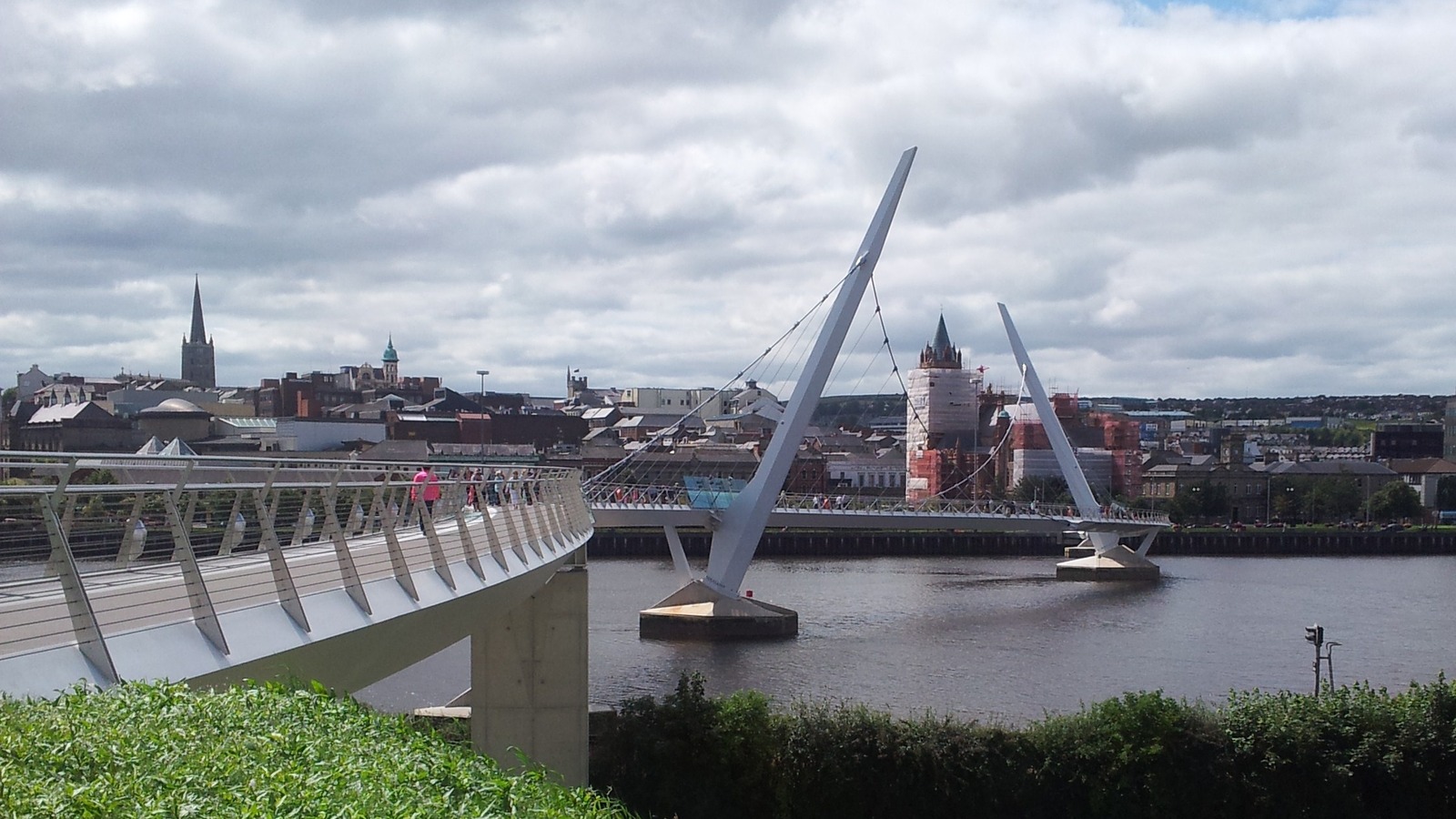 Peace Bridge spanning the River Foyle in Derry-Londonderry with the city skyline beyond, the passenger-facing waterfront served by Foyle Port.