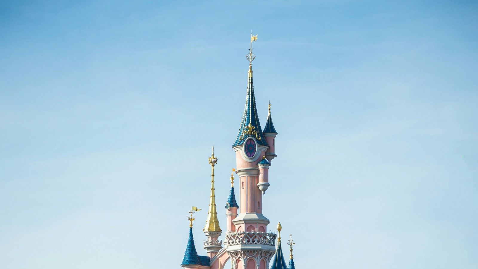 Pink upper tower and blue and gold spire of Sleeping Beauty Castle at Disneyland Paris