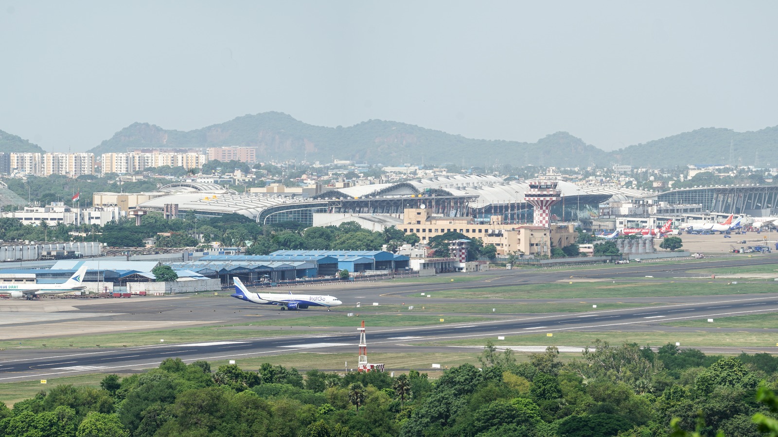 Chennai International Airport terminals, control tower, and runway, with an IndiGo jet on the taxiway