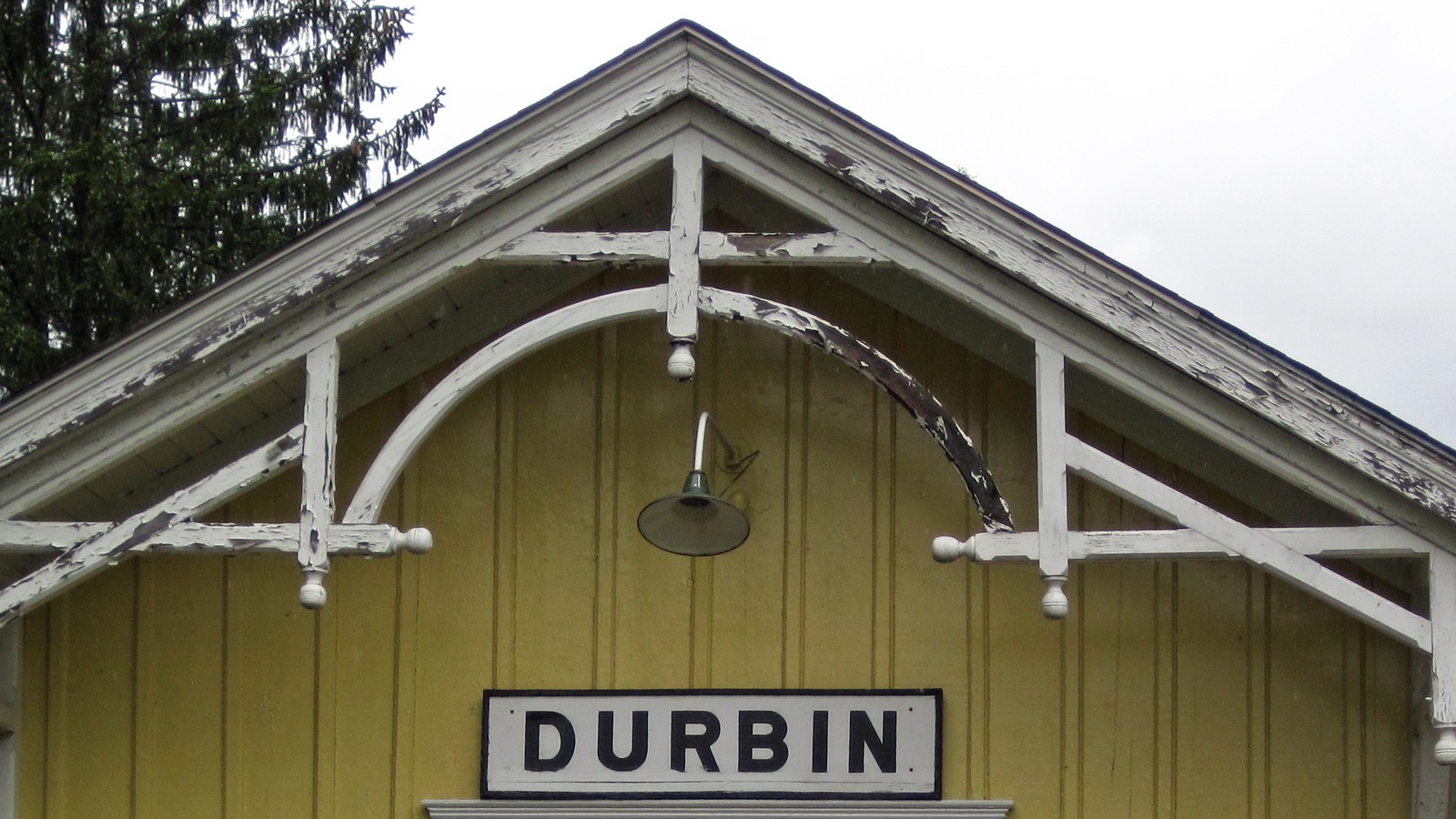 Yellow Durbin, West Virginia railroad depot gable with peeling white trim and a DURBIN station sign