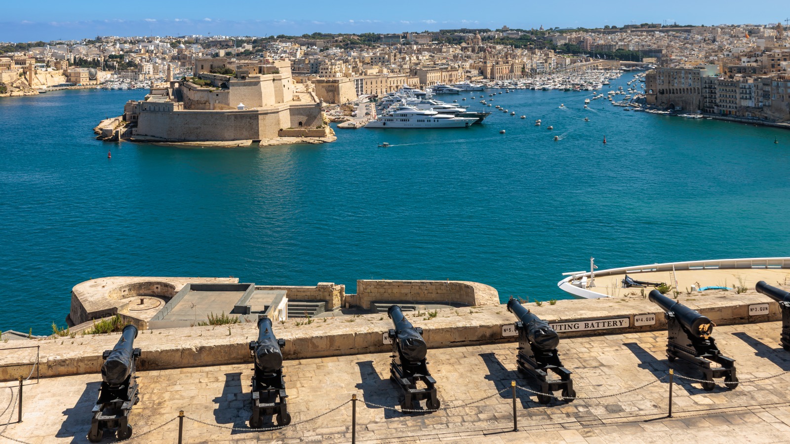 Cannons of the saluting battery at the Upper Barrakka Gardens overlooking Valletta's Grand Harbour and Fort St Angelo, Malta