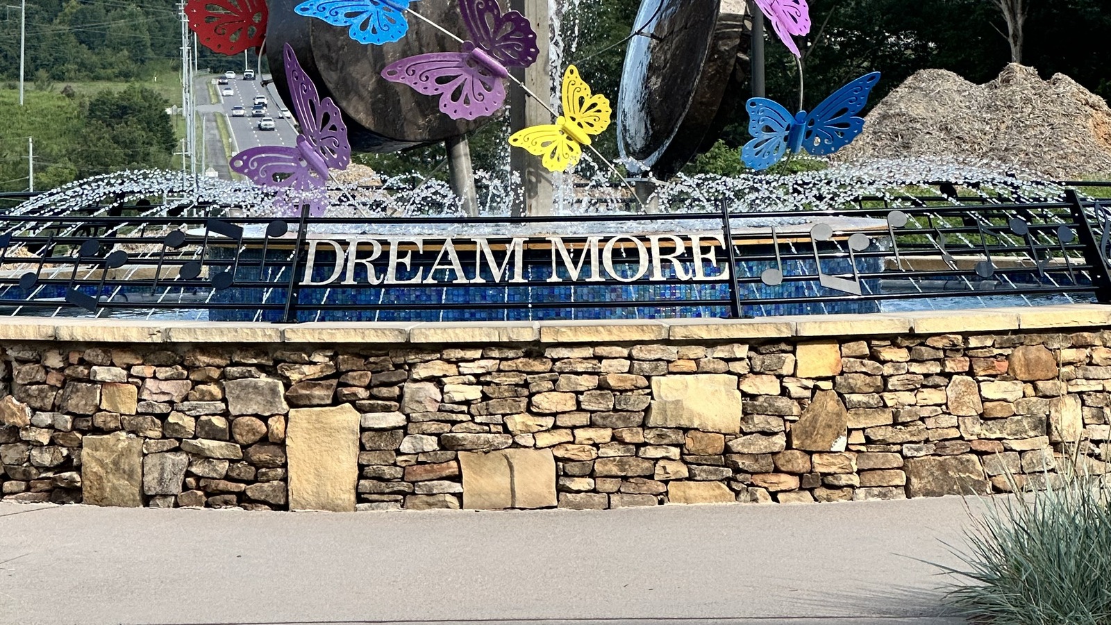 DreamMore Resort entrance fountain with a readable DREAM MORE sign, guitar sculptures, and colorful butterflies in Pigeon Forge, Tennessee