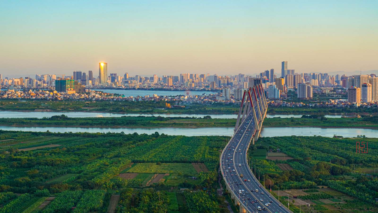 Hanoi skyline at sunrise with the Nhat Tan Bridge crossing the Red River toward the city's high-rises