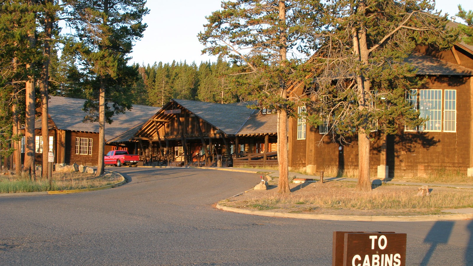 Yellowstone Lake Lodge wooden lodge buildings, paved driveway, and a To Cabins directional sign