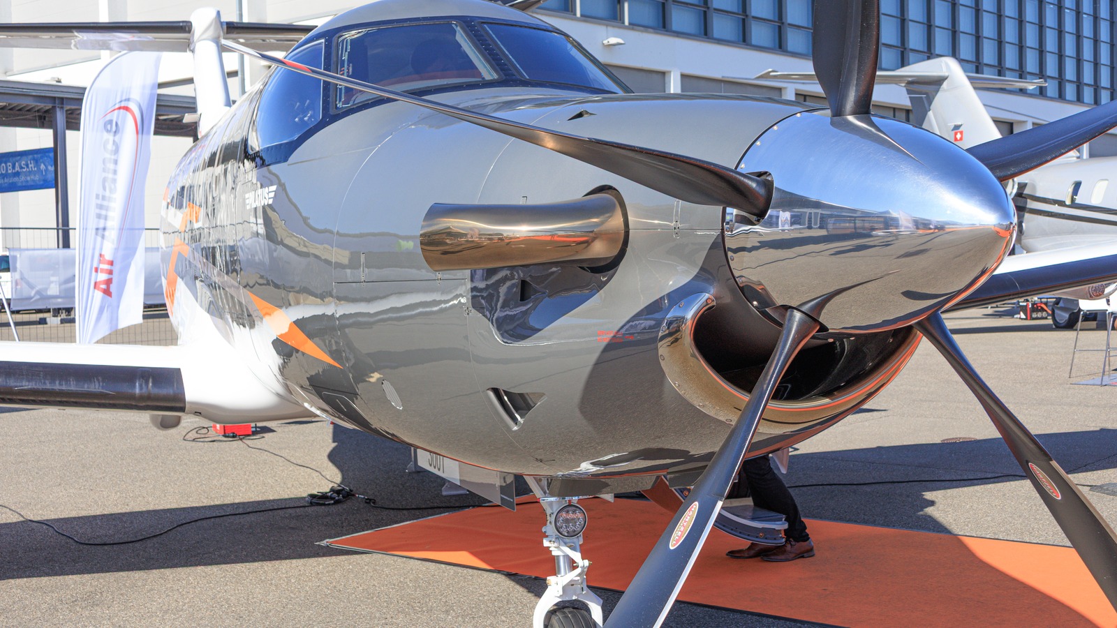 Silver Pilatus PC-12 PRO single-engine turboprop on outdoor display, nose and propeller close view