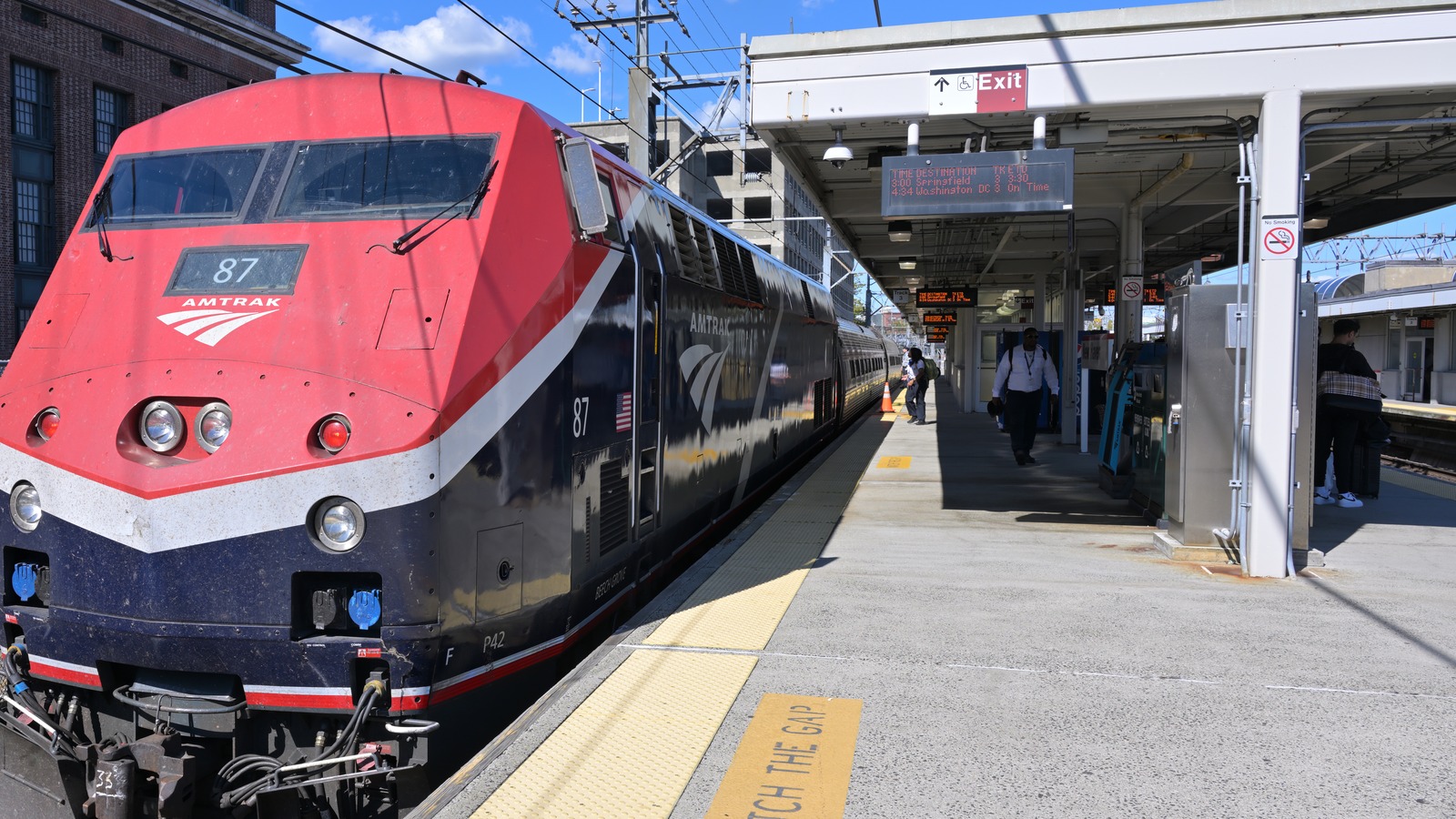 An Amtrak locomotive numbered 87 stands at a sunlit platform at New Haven Union Station in Connecticut