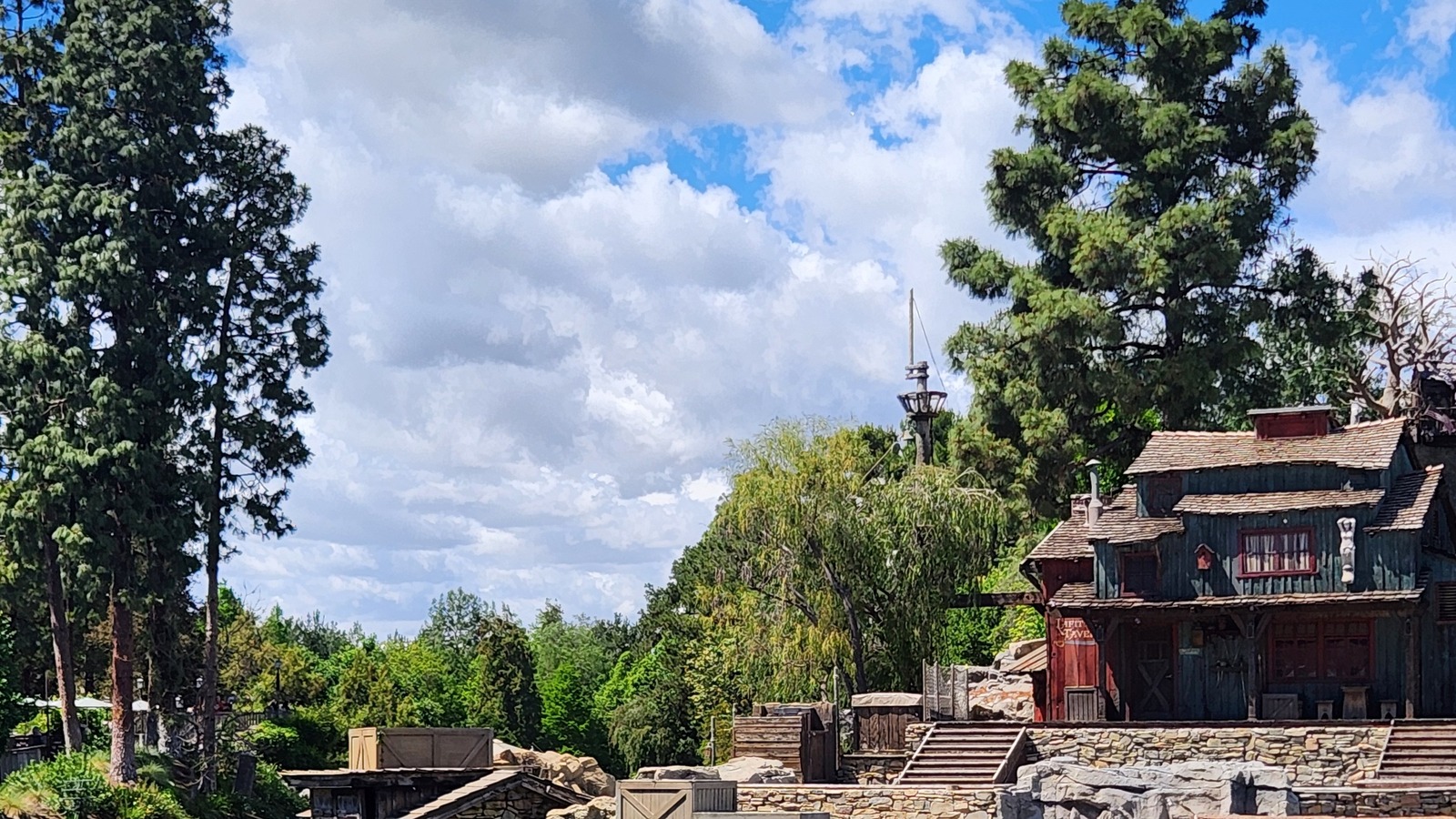 Pirate's Lair buildings and lookout mast on Tom Sawyer Island at Disneyland, viewed across the Rivers of America in April 2026.