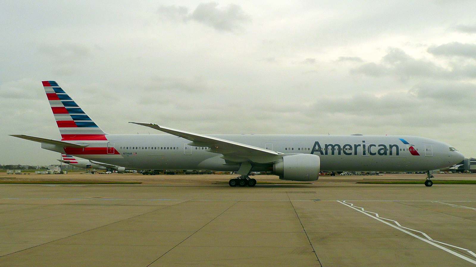 American Airlines Boeing 777-300ER taxiing at London Heathrow Airport under a grey sky