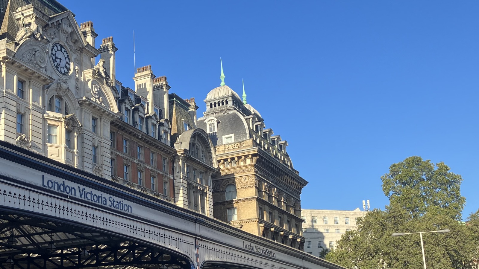 Exterior of London Victoria Station with the station name on the canopy against a clear sky