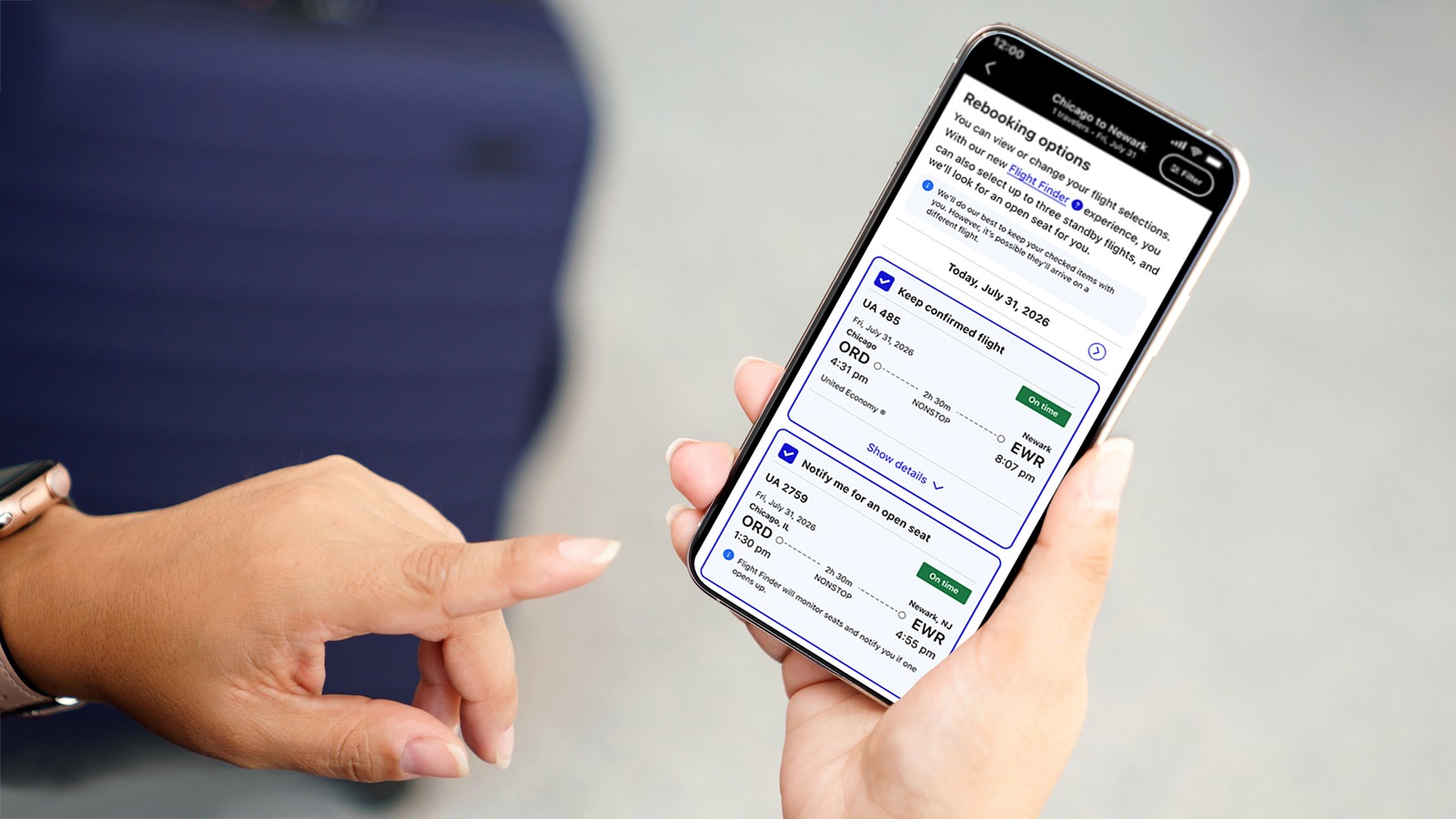 A traveler holds a phone showing the United app Rebooking options screen for a Chicago to Newark trip, with cards to keep a confirmed flight or get notified of an open seat.
