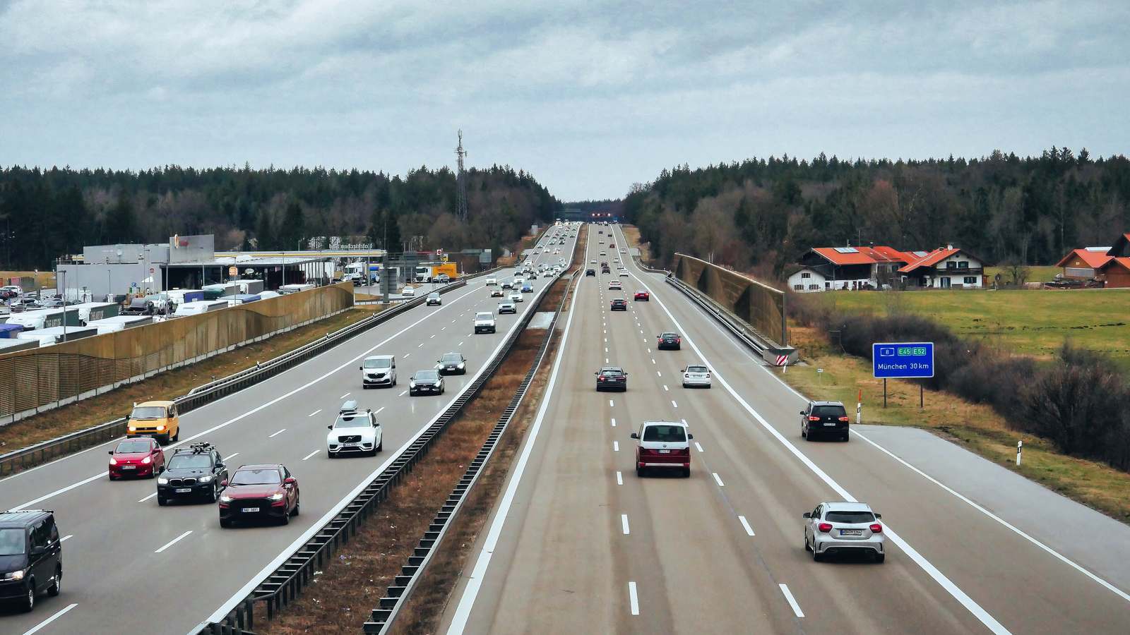 Traffic on the A8 Autobahn near Holzkirchen in Bavaria, with a service station on the left and a sign for Munich 30 km