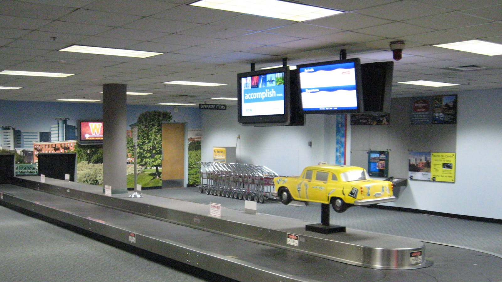 Baggage claim interior at Kalamazoo/Battle Creek International Airport, with a carousel and a yellow taxi sculpture