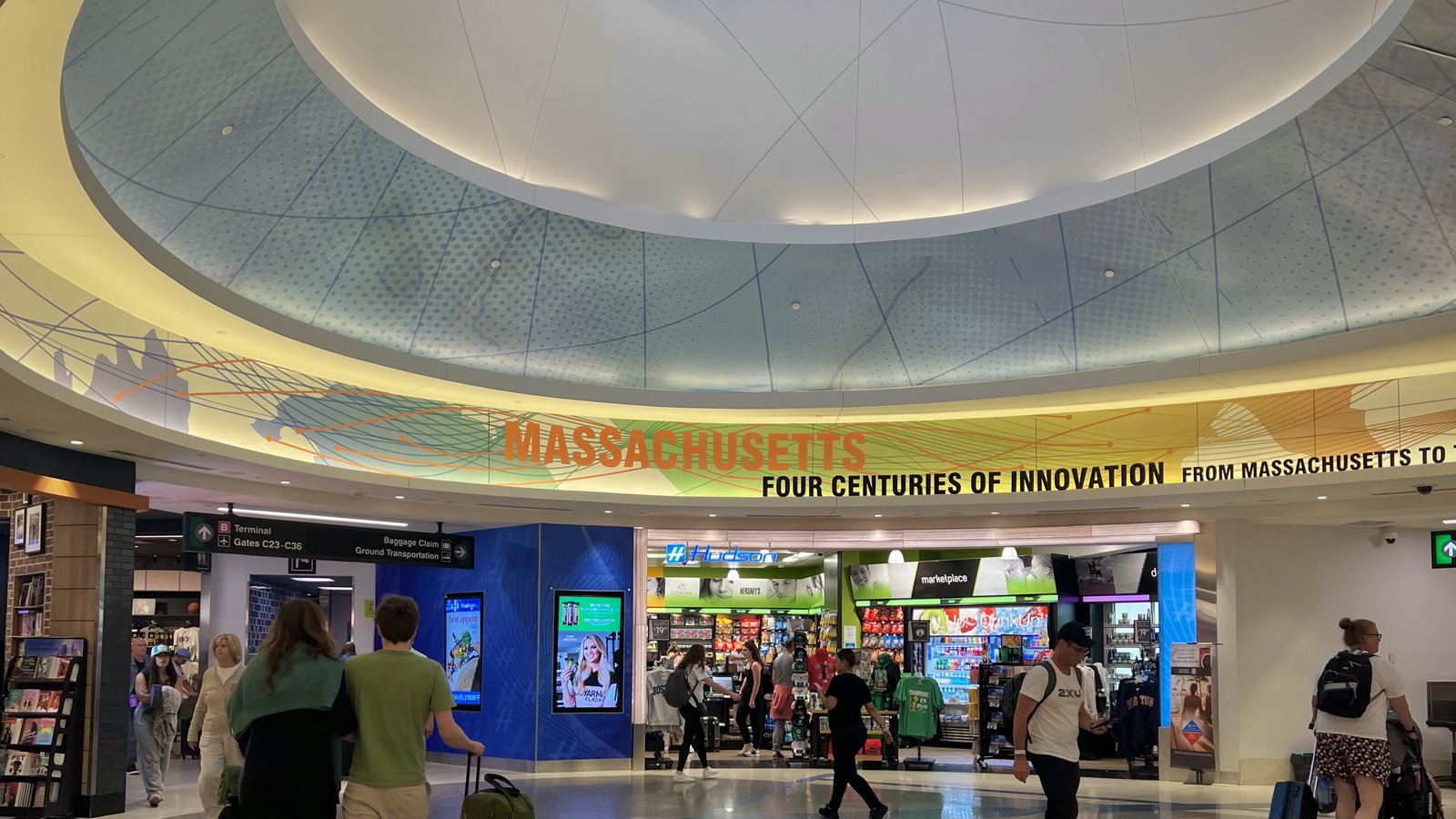 Travelers walk through a Terminal C concourse at Boston Logan International Airport under the Massachusetts rotunda