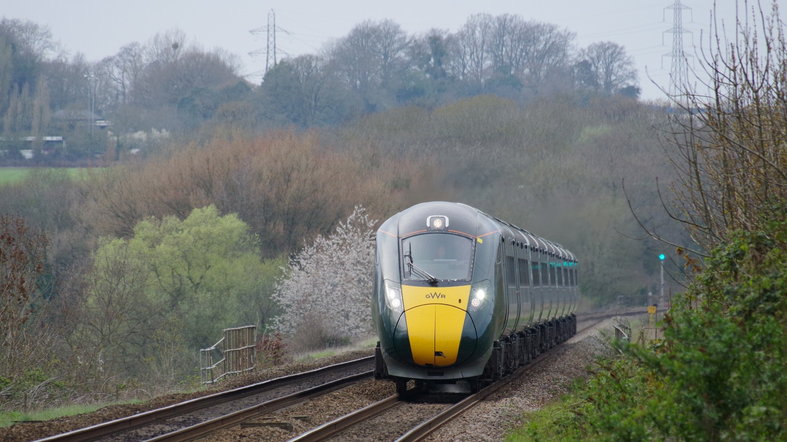 A Great Western Railway Class 800 train with a yellow nose travels along a UK main line.