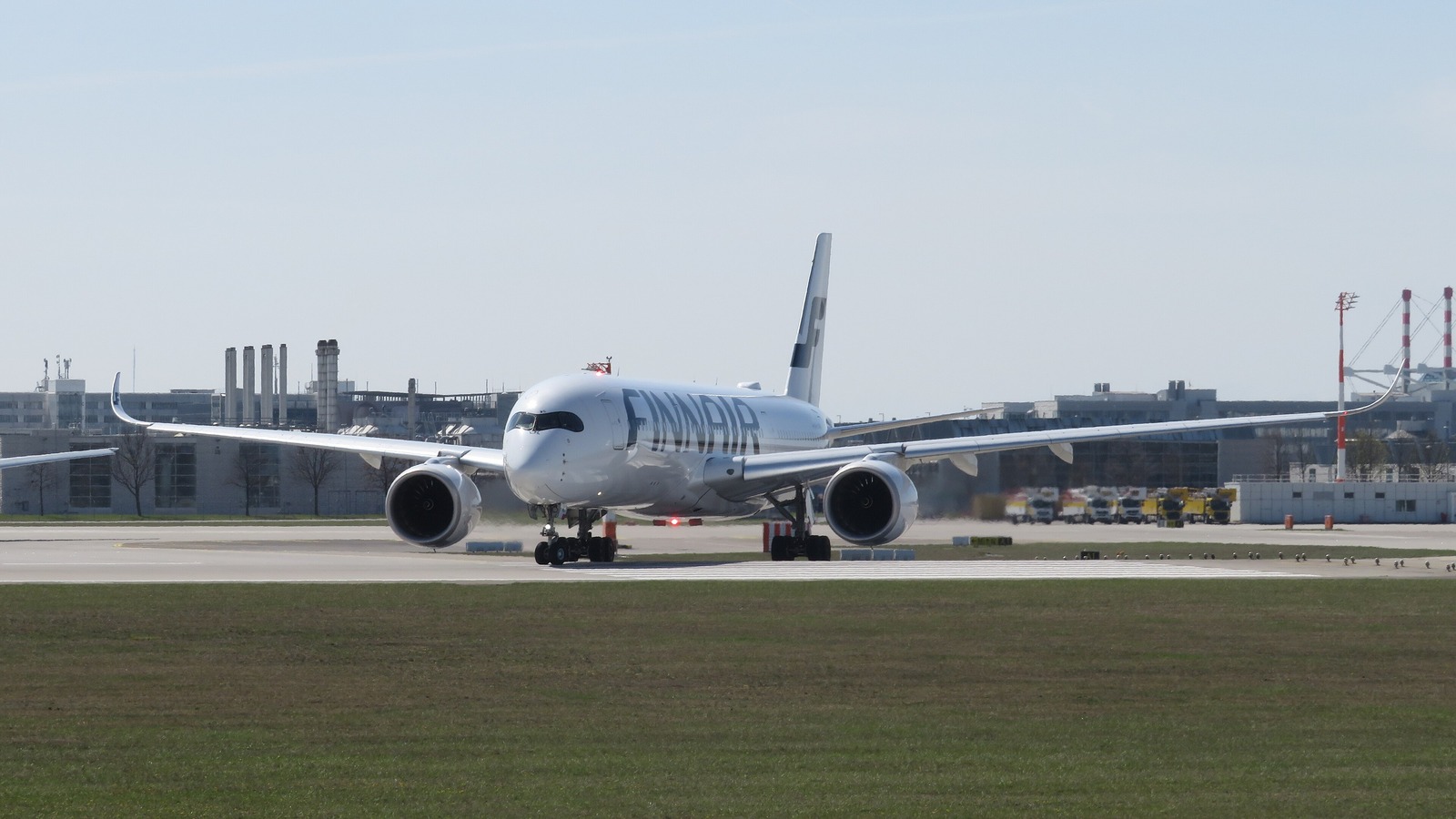 A white Finnair Airbus A350-900 taxiing head-on toward the camera on an airport taxiway under a clear blue sky.