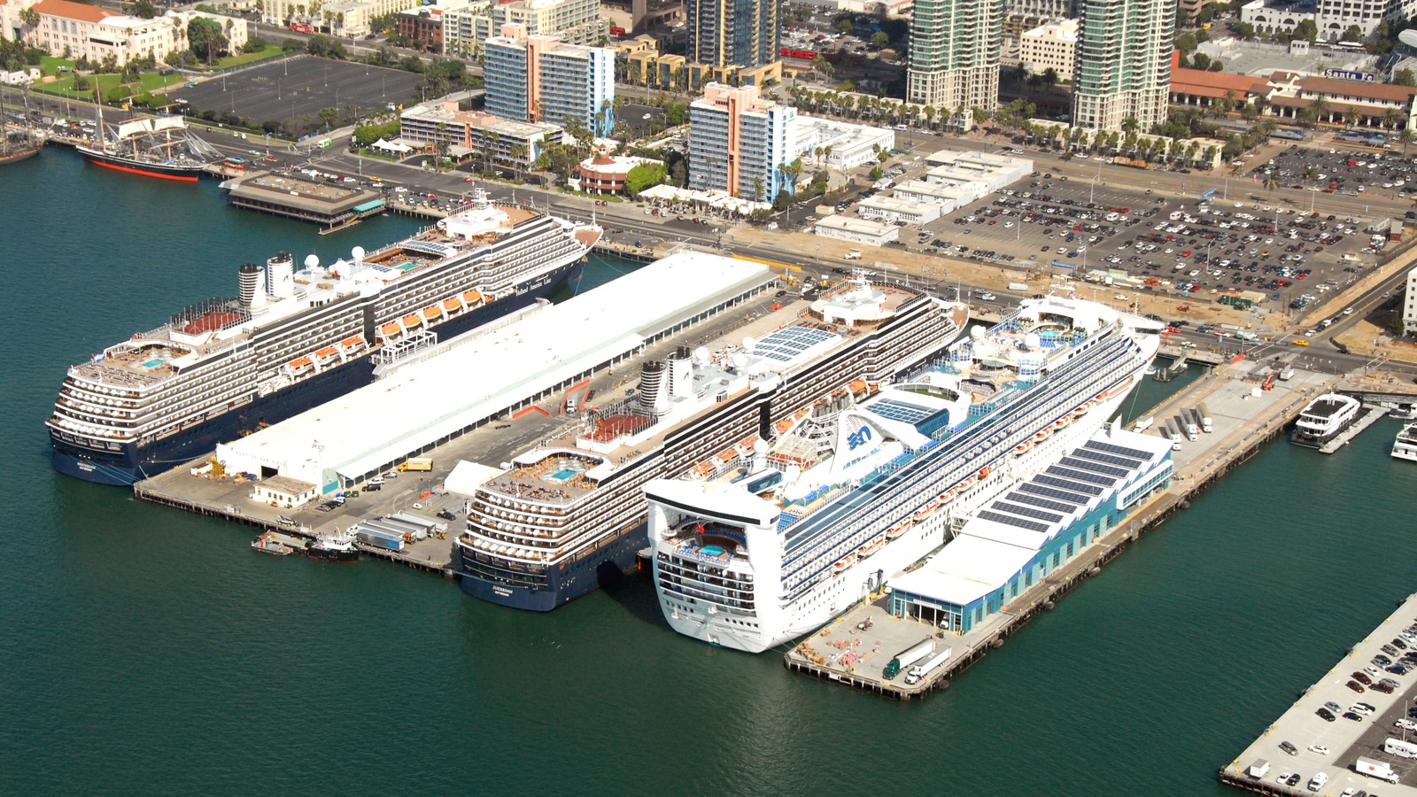 Aerial view of three cruise ships berthed alongside the B Street Pier cruise terminal at the Port of San Diego, with the downtown San Diego skyline and the Santa Fe Depot behind them